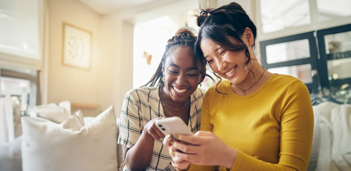 Two girls smiling looking at their phone